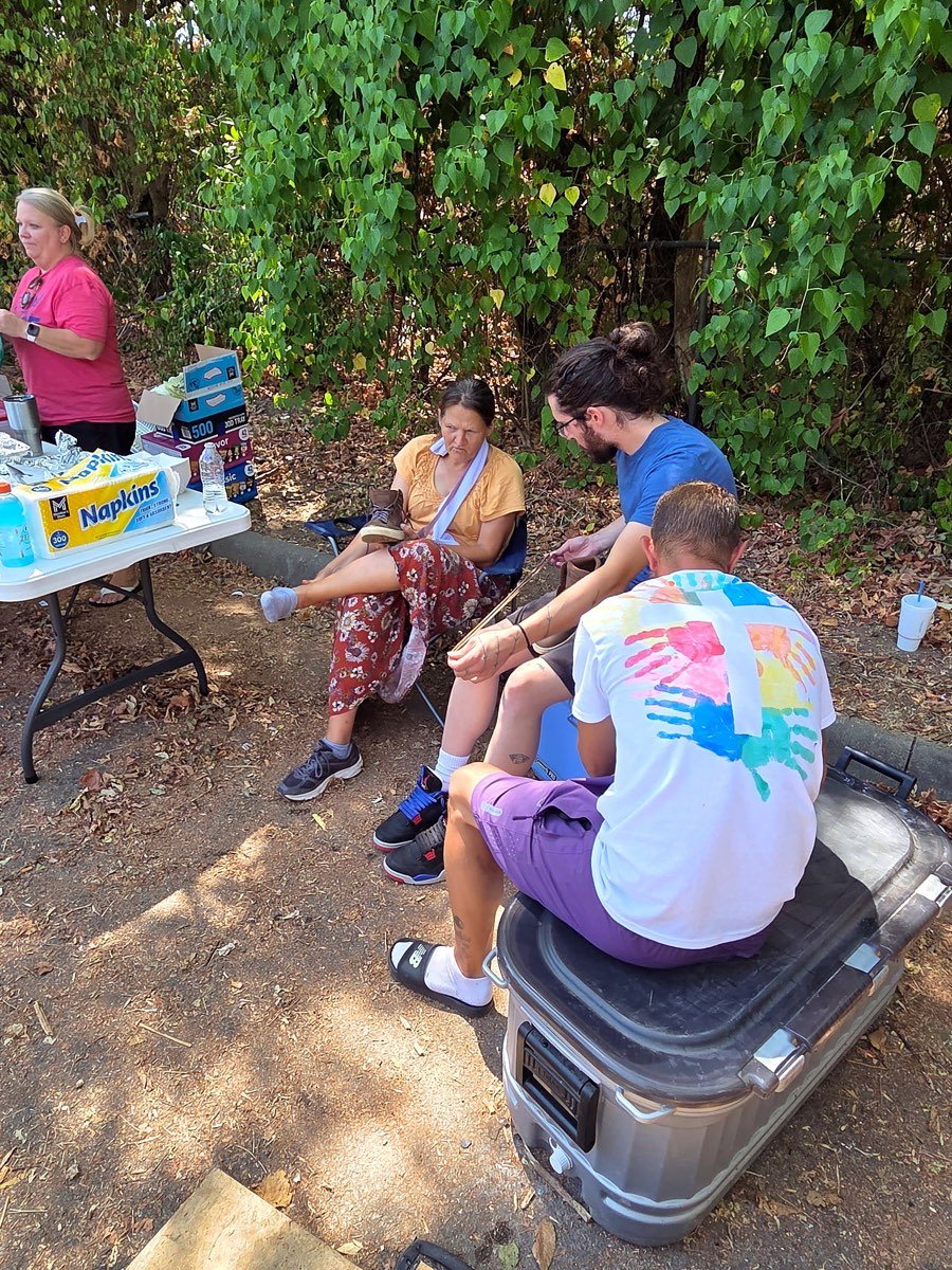 Volunteers sitting and talking with a neighbor in the shade